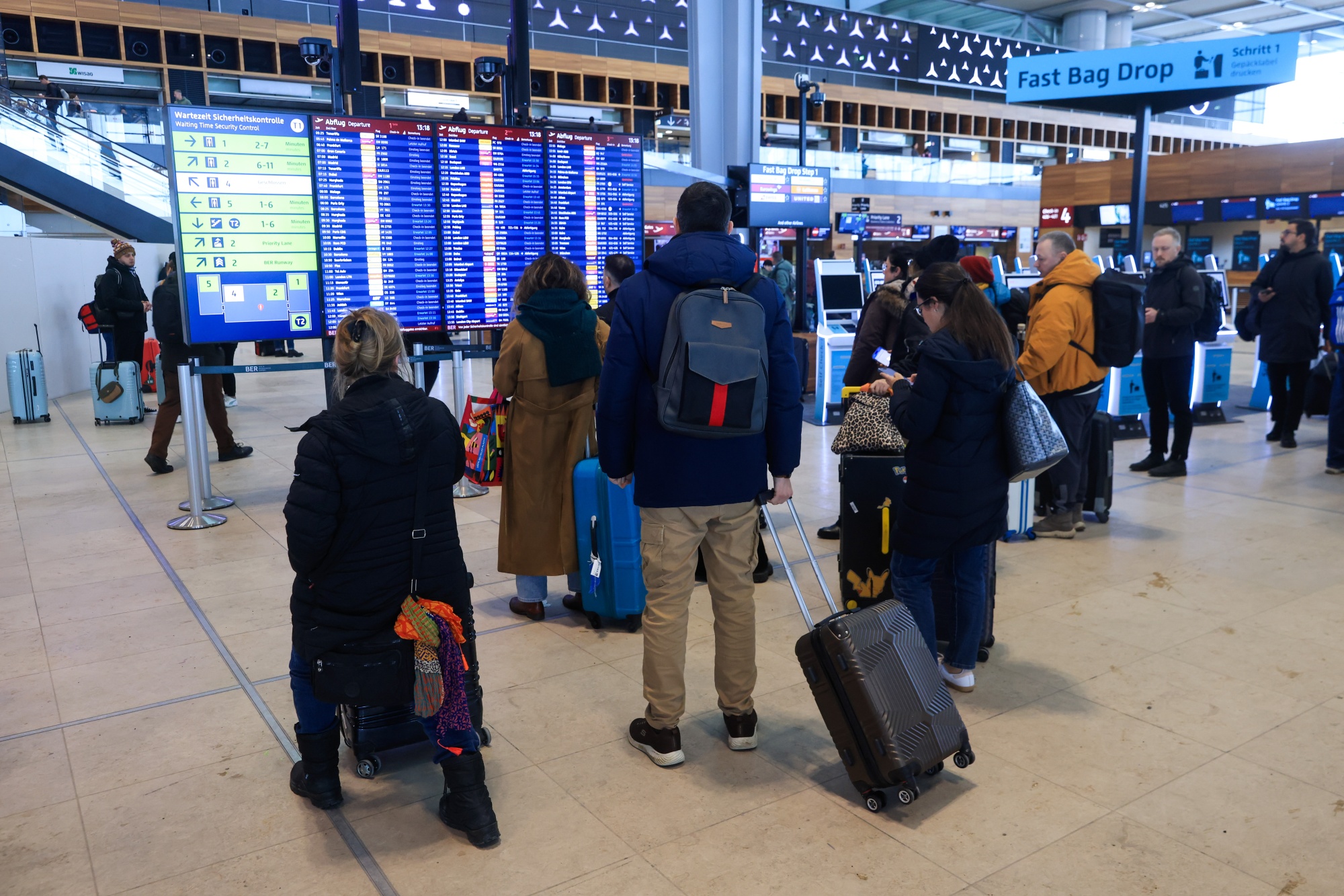 Travelers look at flight information boards at Berlin Brandenburg Airport