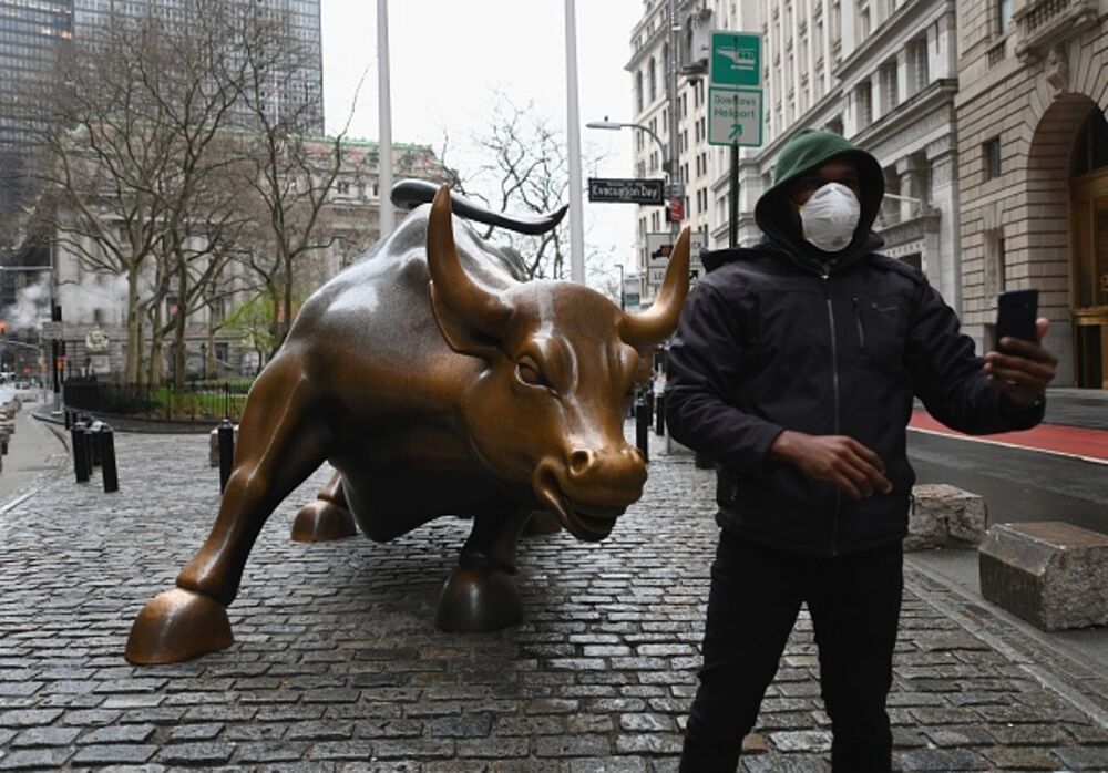 A man wearing a face mask takes a selfie near the New Stock Exchange in New York City.