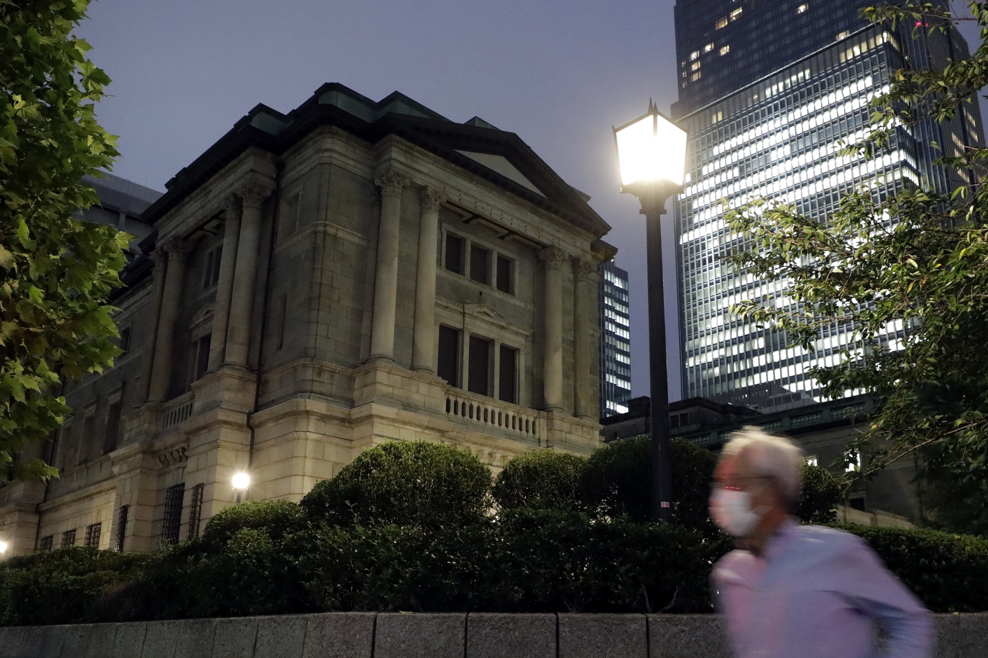 A pedestrian wearing a protective mask passes by the Bank of Japan (BOJ) headquarters at dusk in Tokyo, Japan.