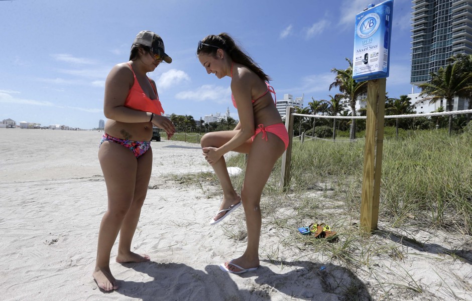 Sunbathers apply sunscreen, Friday, March 13, 2015, in Miami Beach.