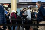 Travelers wearing protective masks stand in the TSA line at Ronald Reagan National Airport&nbsp;in Arlington, Virginia.
