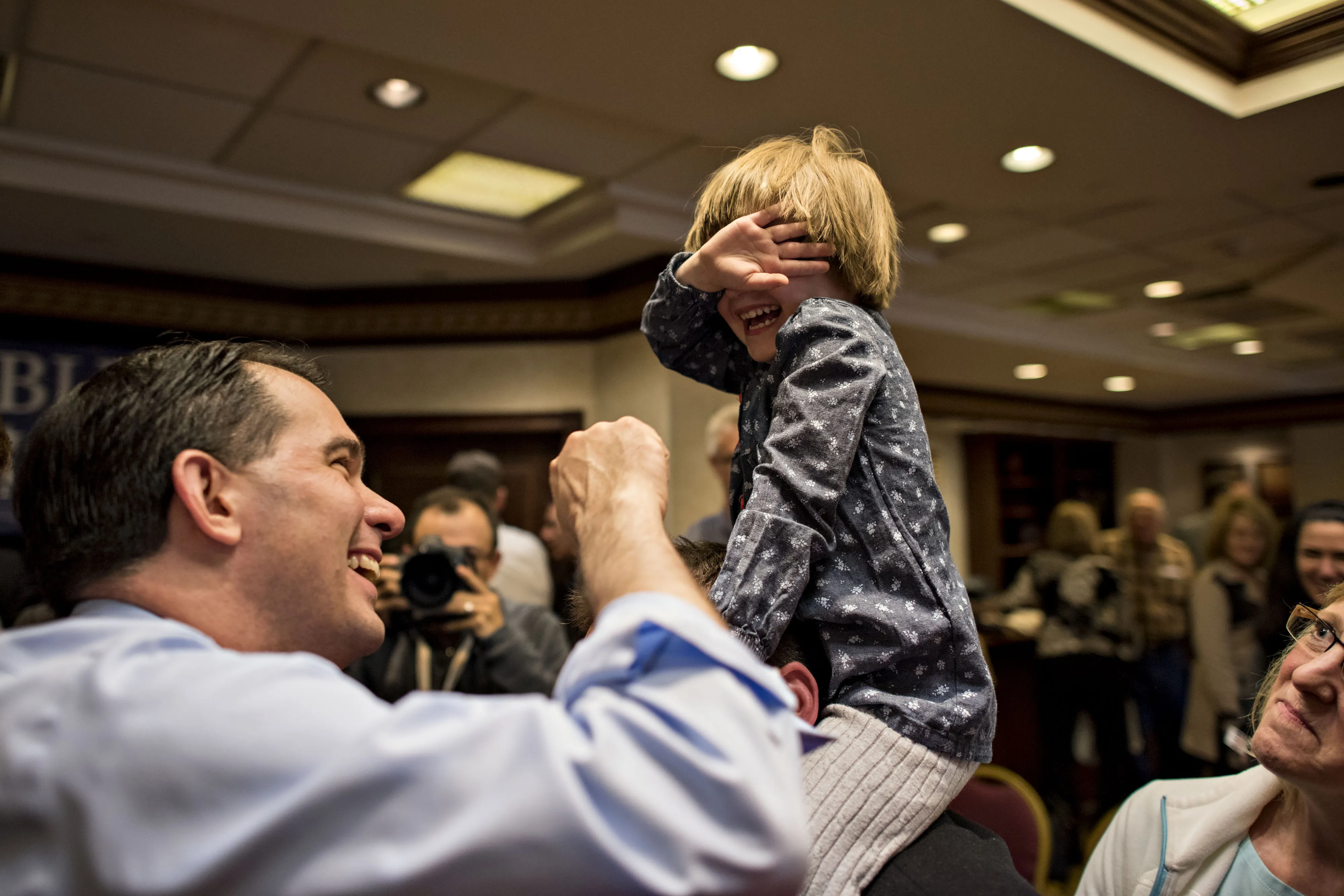 Scott Walker, governor of Wisconsin, jokes with a shy young attendee, who's name was declined by her parent, during a rally for U.S. Representative Rod Blum of Dubuque in Cedar Rapids, Iowa, U.S., on Friday, April 24, 2015.
