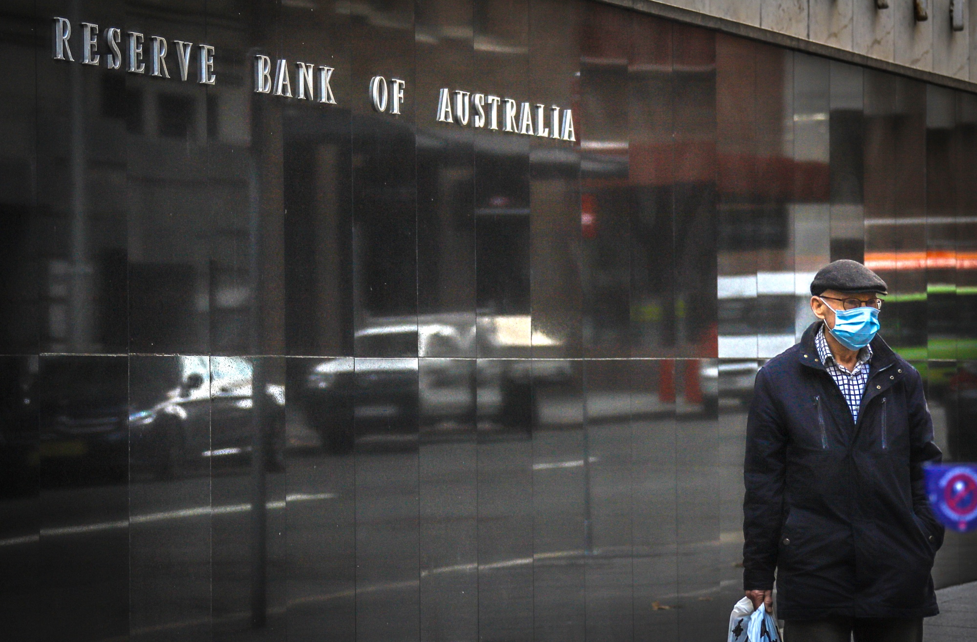A pedestrian wearing a face mask walks past the Reserve Bank of Australia&nbsp;in Sydney.