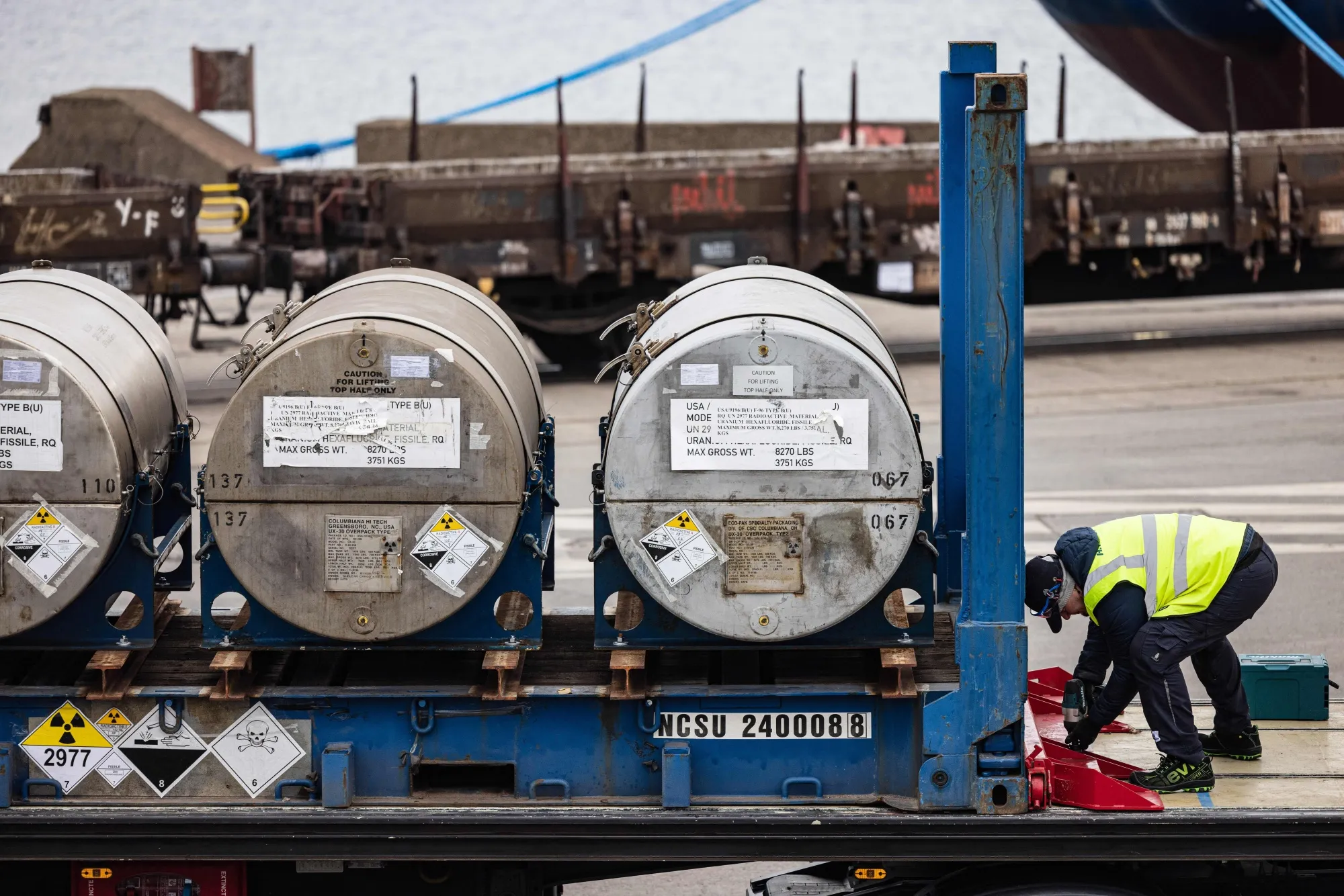 A worker fixes cylinders of uranium onto a transport truck.