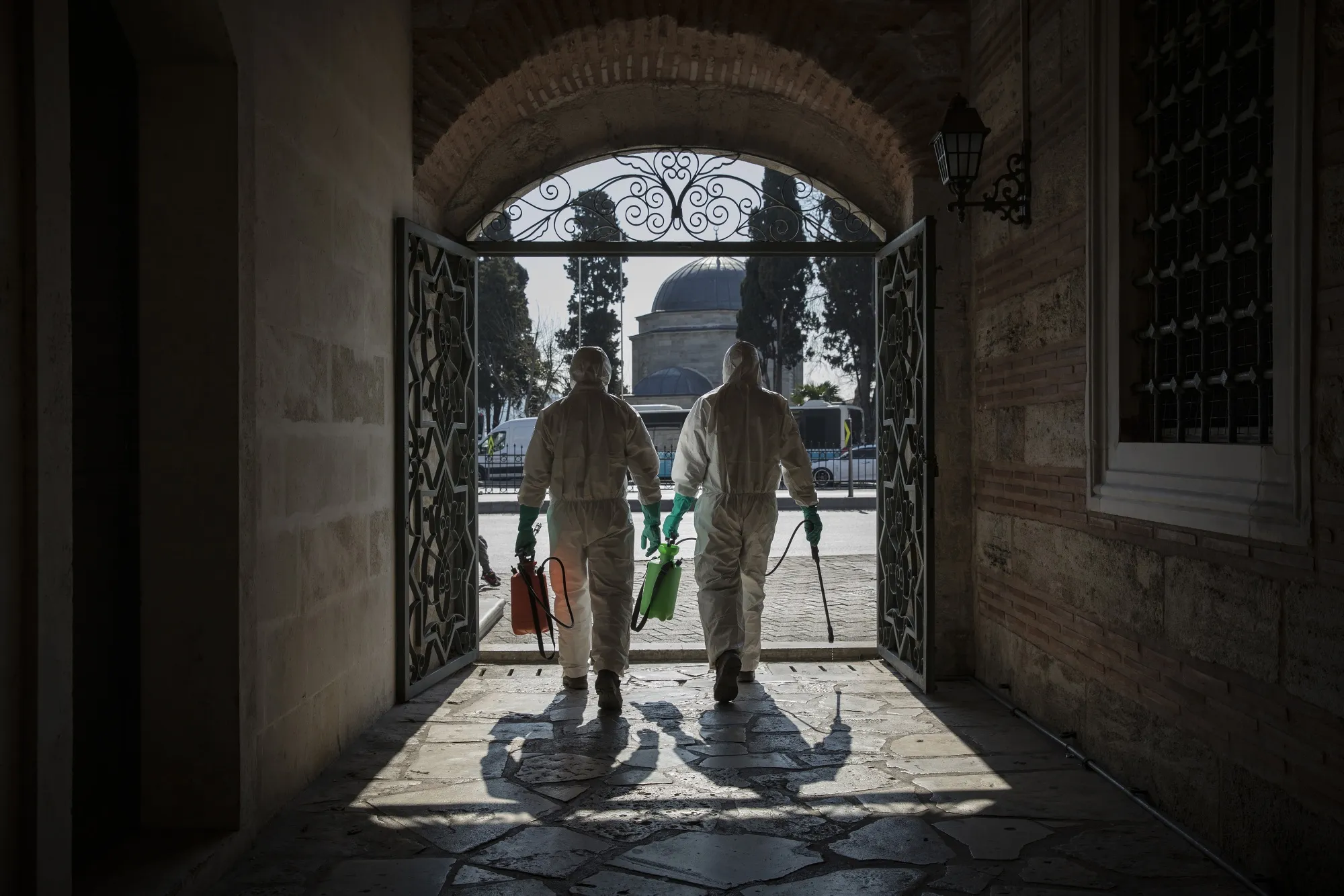 Metropolitan municipality workers wearing a hazmat suits walk through a public area carrying disinfectant spray in Istanbul.
