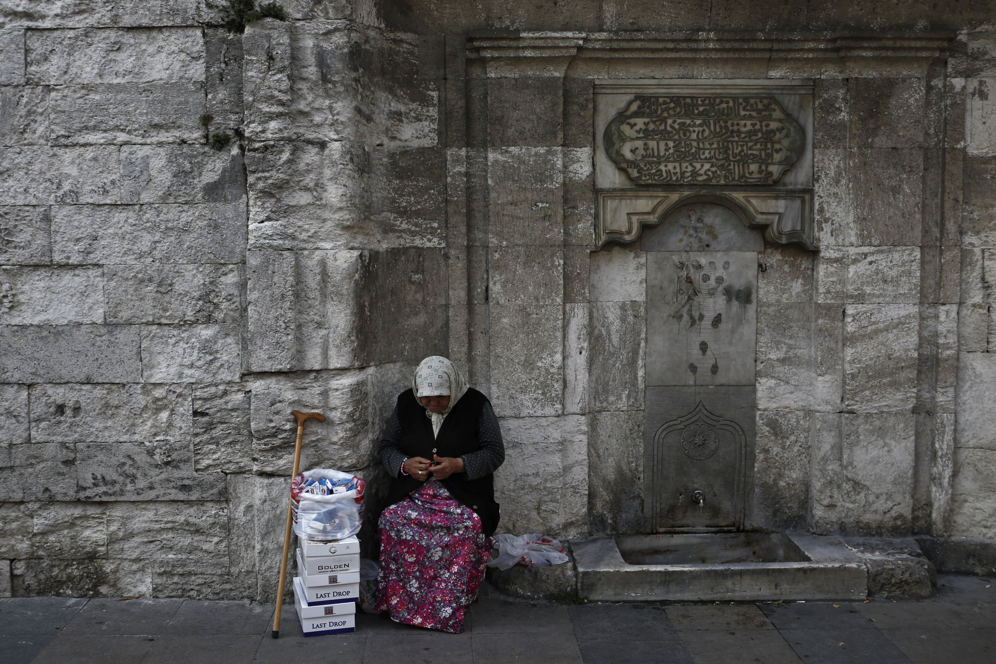 An elderly woman sells packets of tissues on the roadside in Istanbul, Turkey.