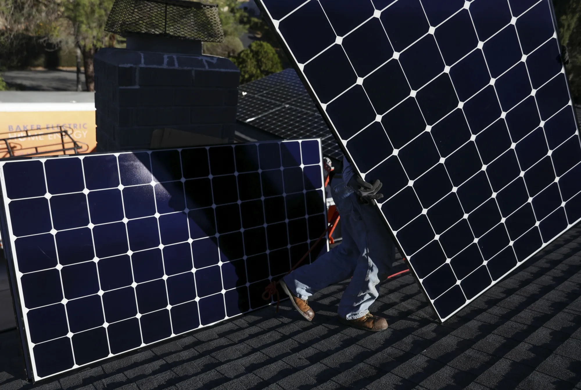 A worker installs solar panels on the rooftop of a home in Poway, California.