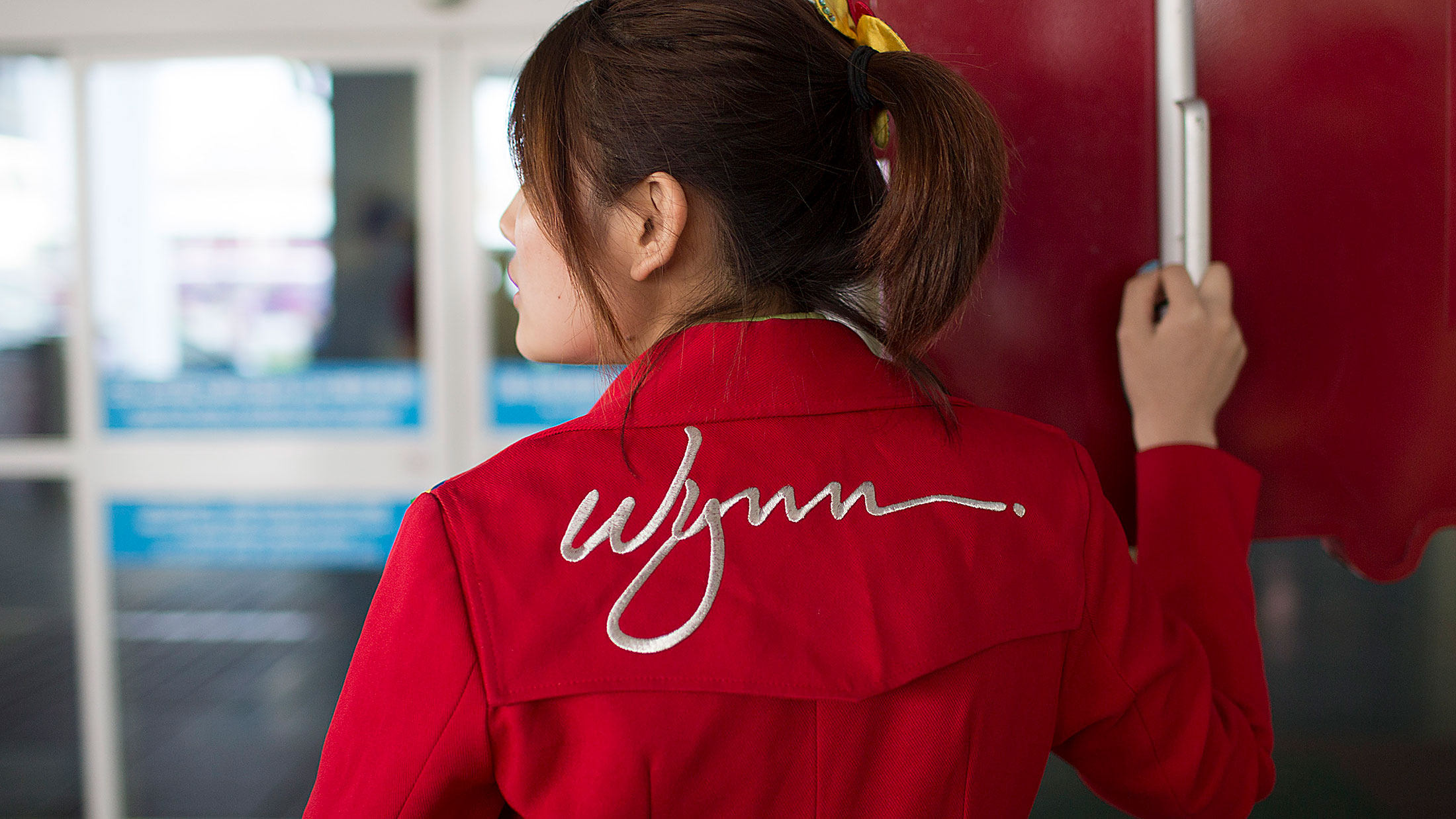 An employee holds a sign for Wynn Macau casino resort outside the ferry terminal in Macau, China.
