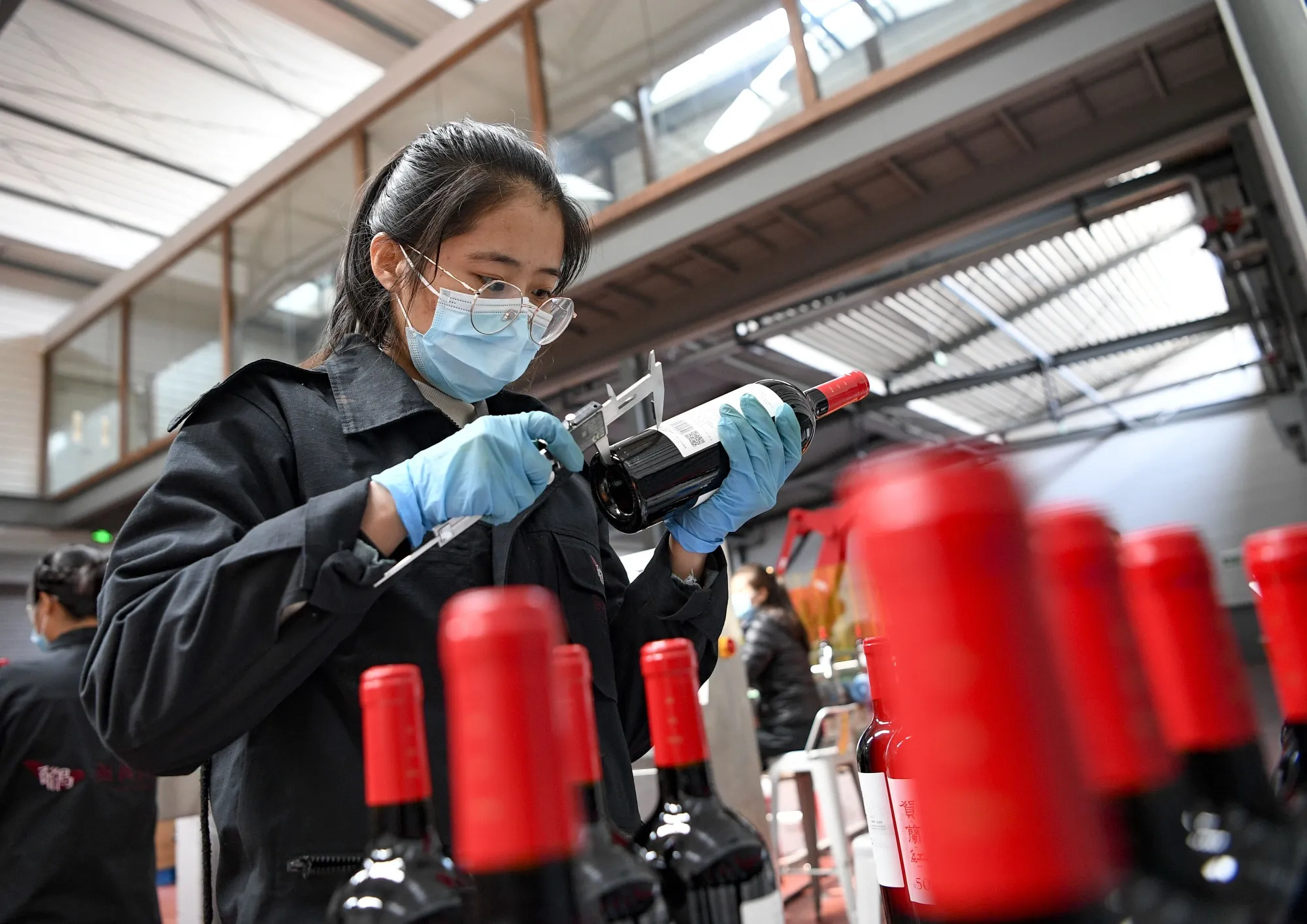 A staff member inspects finished wine products in China’s Ningxia Hui Autonomous Region.