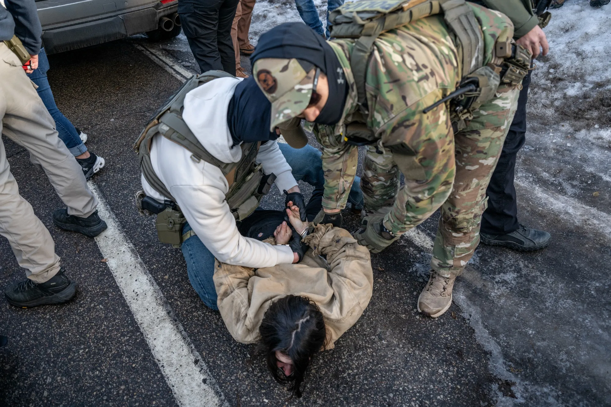 Federal law enforcement agents detain a demonstrator during a raid in south Minneapolis on Jan. 13.