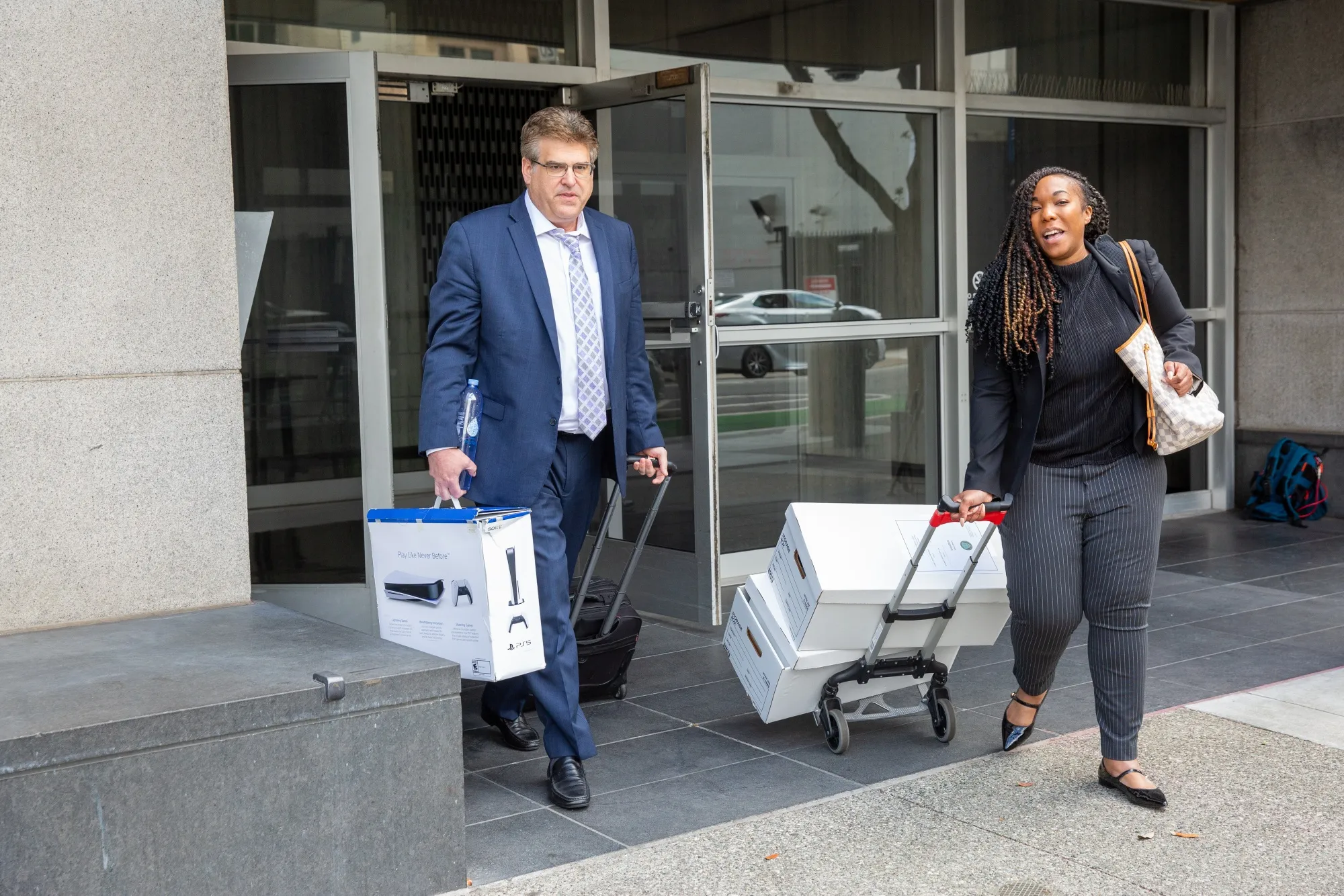 An attorney carrying a Sony PlayStation 5 leaves court in San Francisco.