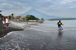 Balinese people pull their fishing net on Amed beach as Mount Agung volcano&nbsp;belches ash,&nbsp;on Bali.