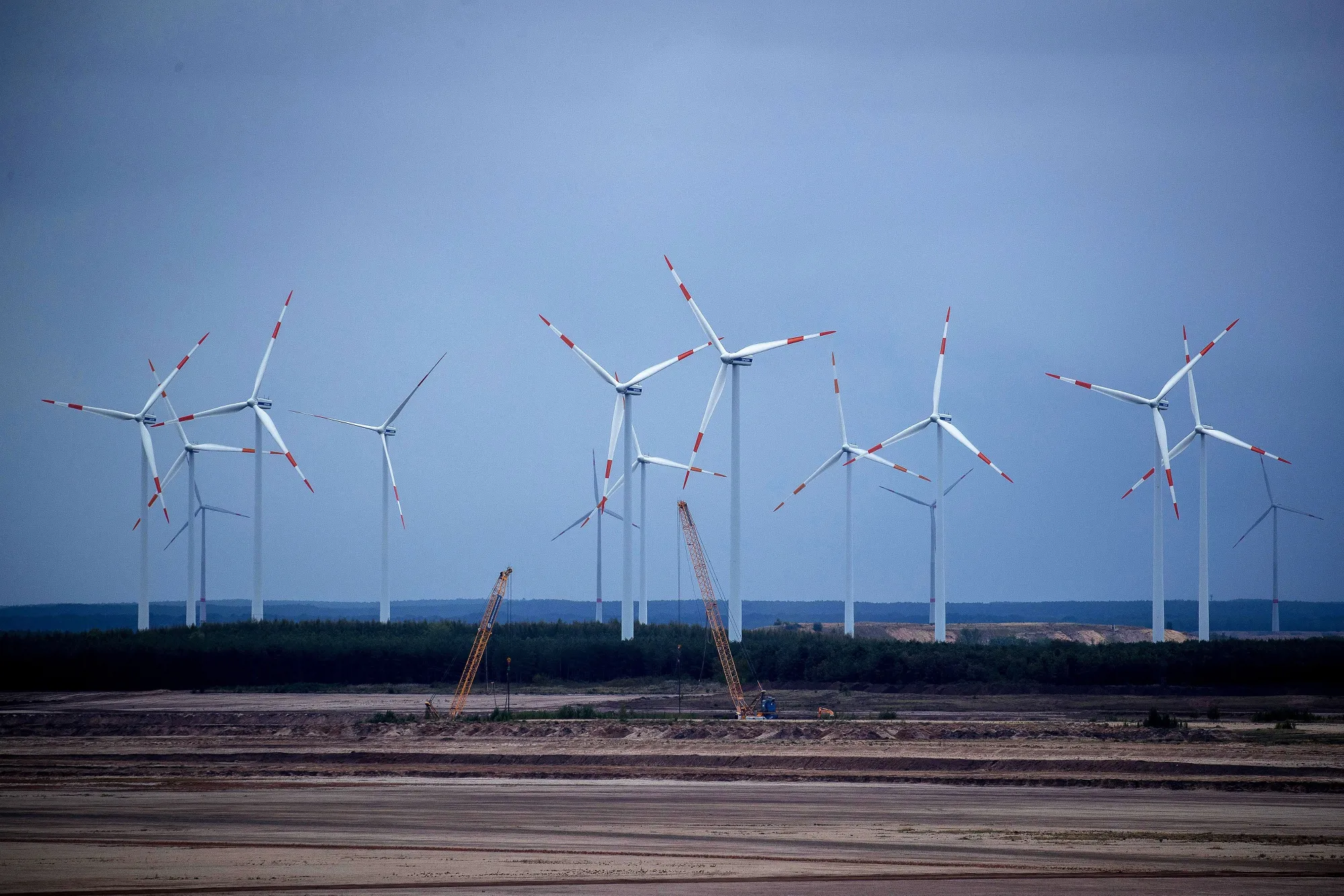 Wind turbines operate beyond an open cast lignite mine in Merzdorf, Germany.