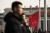 Security personnel stand in front of red flags flying outside the Great Hall of the People following the first session of the 13th National People's Congress (NPC) in Beijing, China.