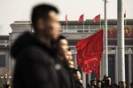 Security personnel stand in front of red flags flying outside the Great Hall of the People following the first session of the 13th National People's Congress (NPC) in Beijing, China.