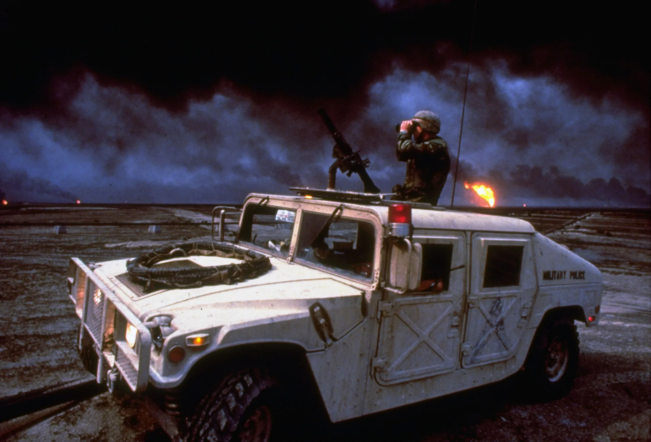 A soldier atop a humvee scans the horizon in Kuwait, dotted with oil well fires set by retreating Iraqi&nbsp;military forces, during the Gulf War. In a world dominated by green energy, security researchers predict, a&nbsp;latter-day Saddam Hussein would have little&nbsp;reason to invade Kuwait to seize its solar parks, as he did in 1990 for its oil wells.
