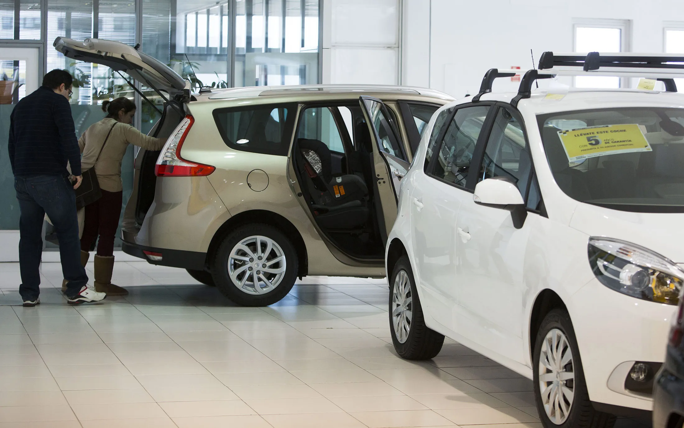 Customers inspect the interior boot space of a new Renault Megane automobile for sale inside a Renault SA dealership in Madrid.
