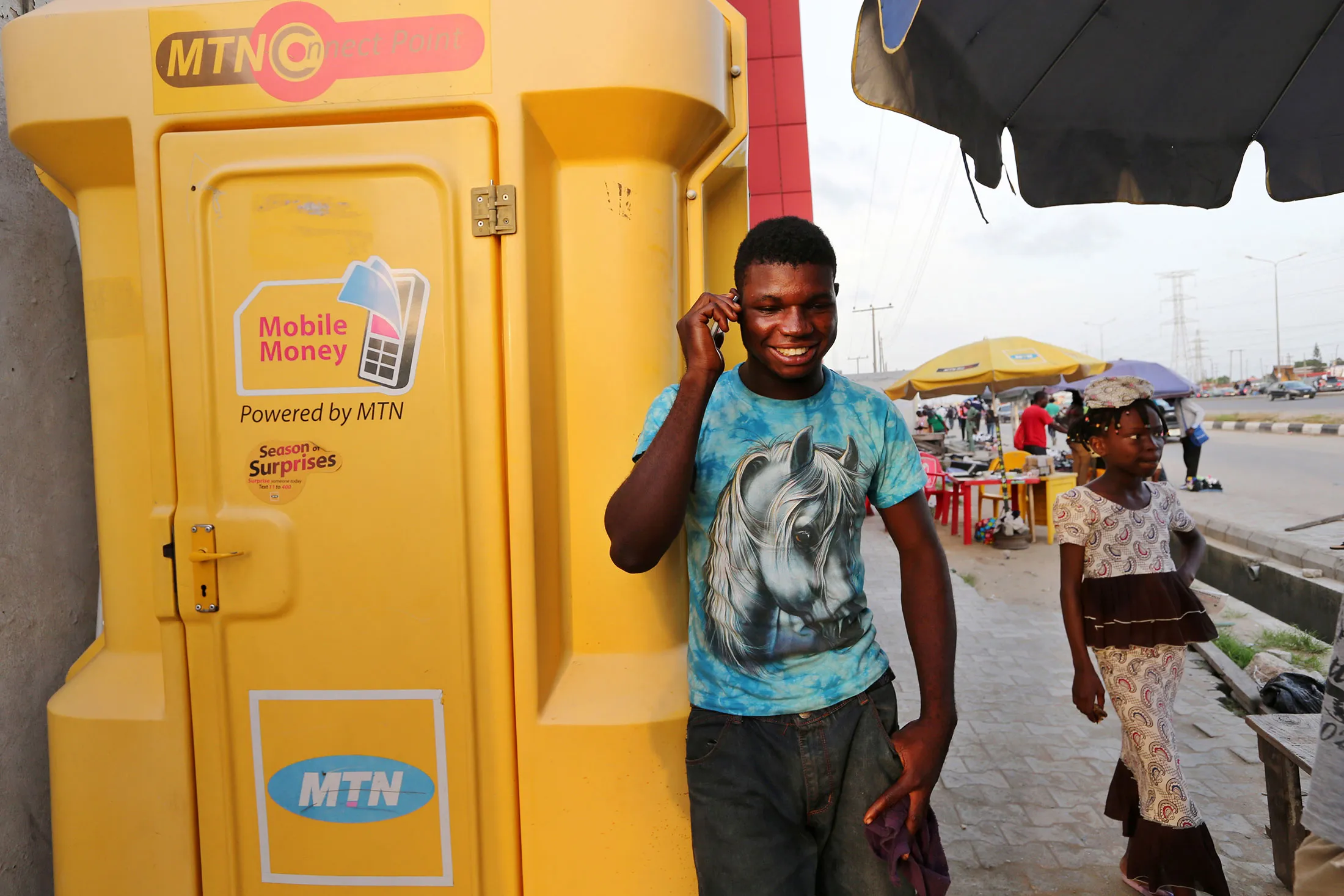 A customer uses a mobile phone beside an MTN Group Ltd. 'Connect Point' in Lagos, Nigeria.
