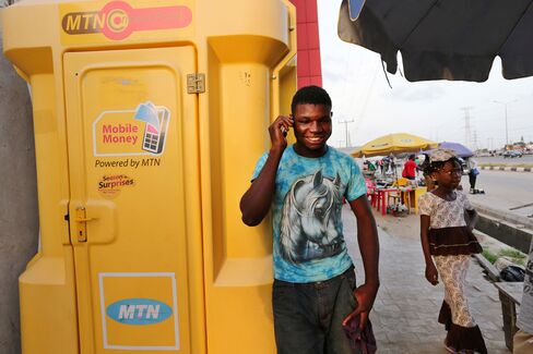 A customer uses a mobile phone beside an MTN Group Ltd. 'Connect Point' in Lagos, Nigeria.