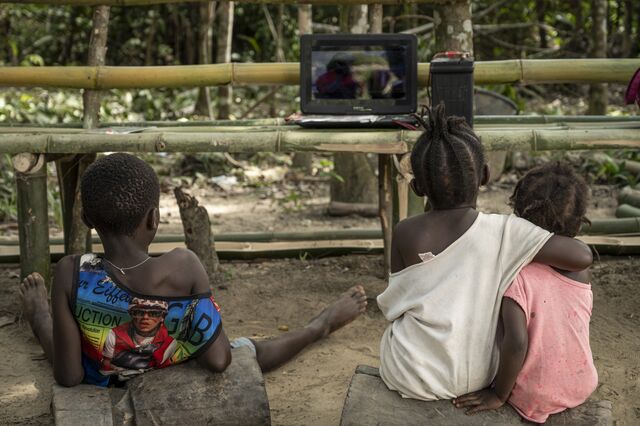 Kids watch a movie on a DVD player powered by a car battery in Jehjeh Town, which has no electricity or running water.