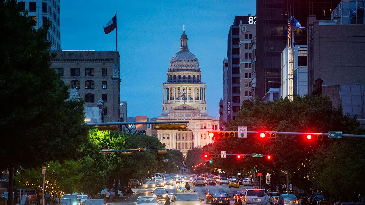 The Texas State Capitol building stands past cars and pedestrians crossing the street at dusk in Austin, Texas, U.S., on Saturday, April 4, 2015.
