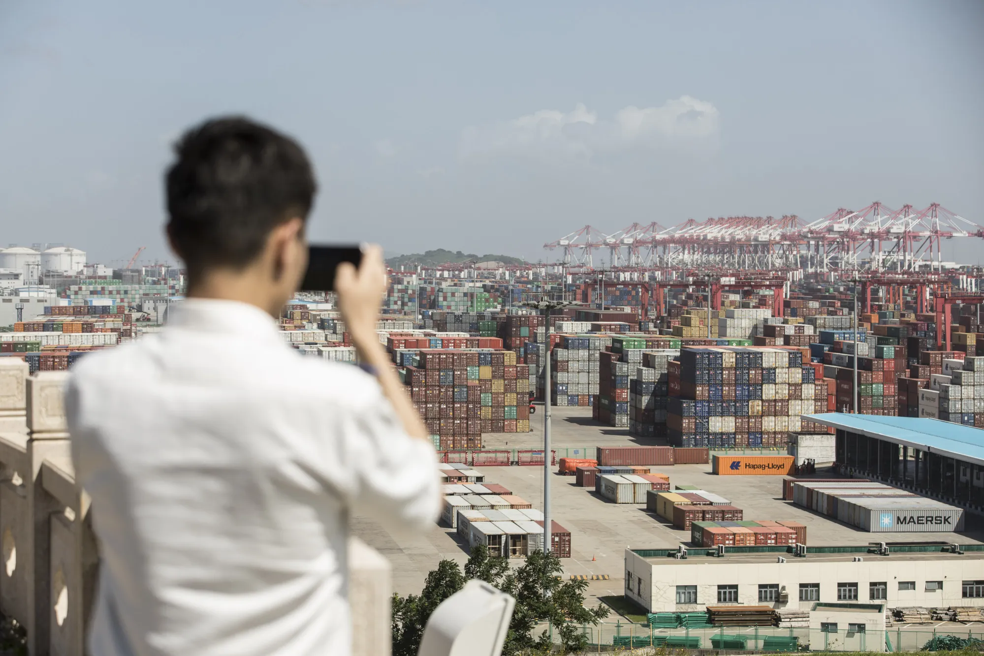 A man takes a picture with his smartphone from a viewing platform overlooking the Yangshan Deep Water Port in Shanghai.