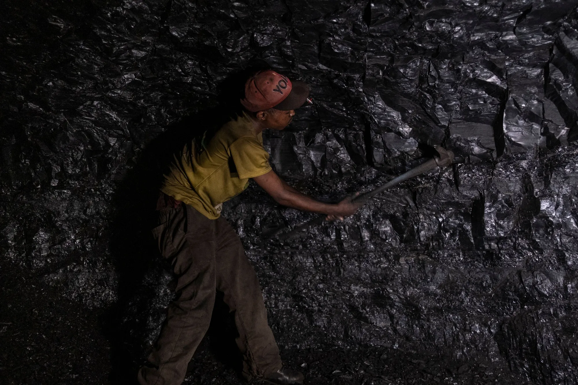 A miner uses a pickaxe to gather&nbsp;coal at an abandoned coal mine in Ermelo, South Africa.
