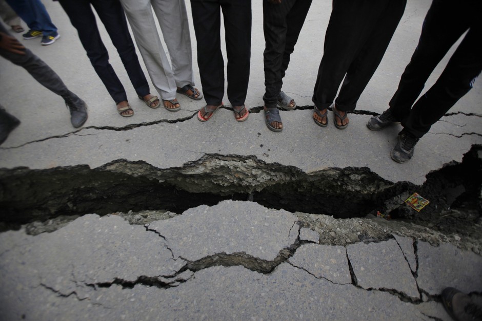 Nepalese people look at a cracked road after the recent earthquake in Kathmandu. 