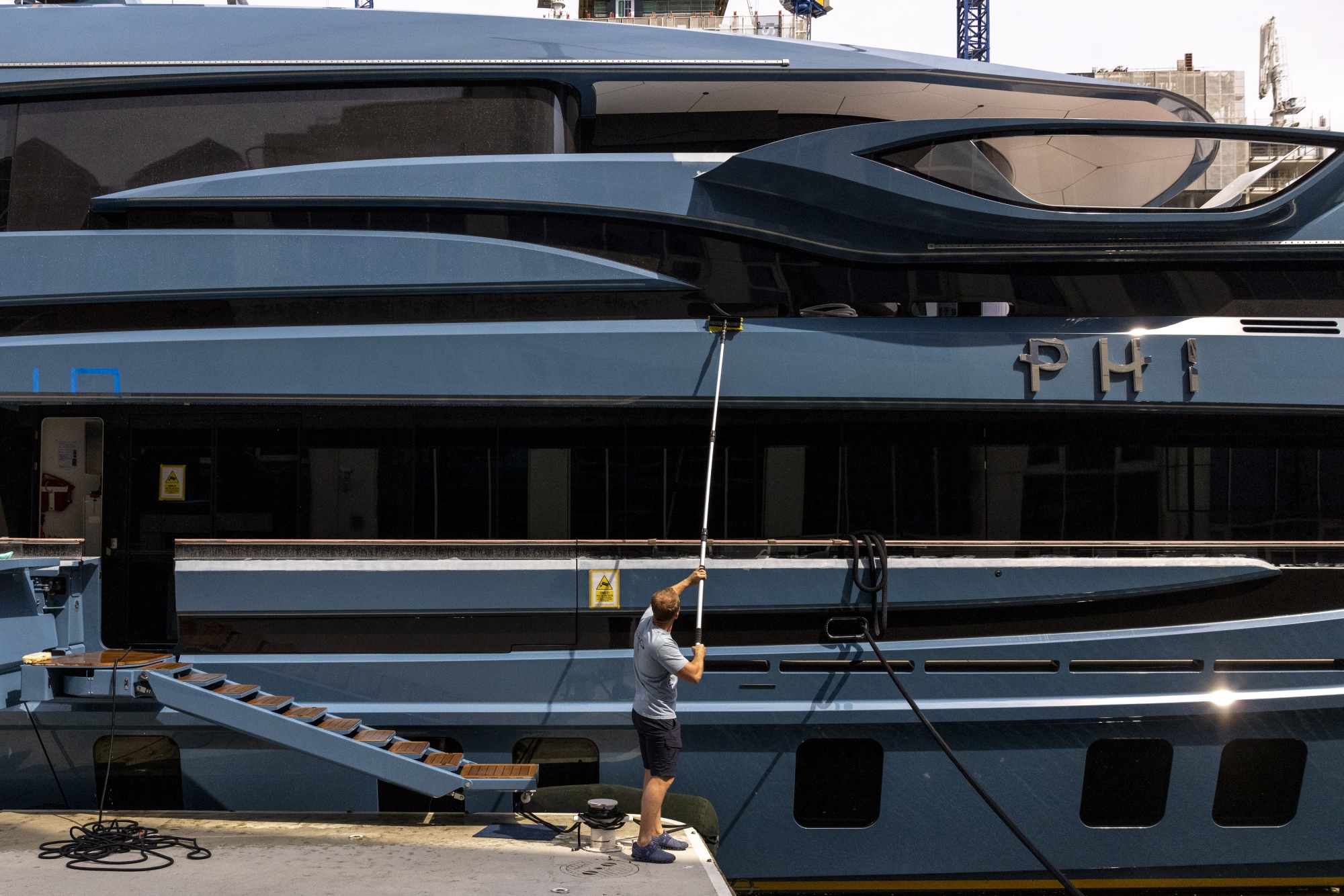 A worker cleans the Phi 192-foot superyacht impounded at a dock near Canary Wharf in London, UK, on Thursday, May 18, 2023.