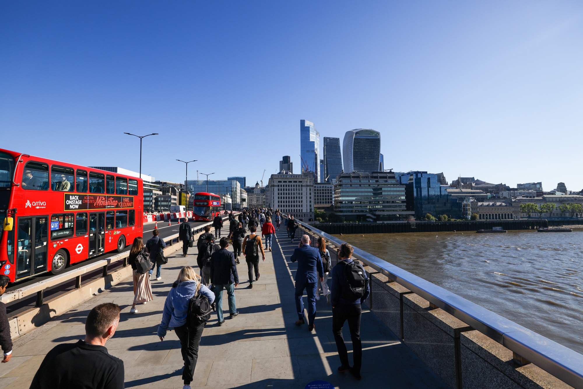 Commuters walk across London Bridge towards the City of London.