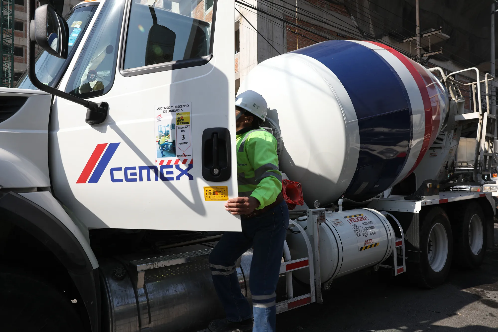 A worker climbs into the driver seat of a Cemex SAB cement truck at a construction site in Mexico City in January, 2017.