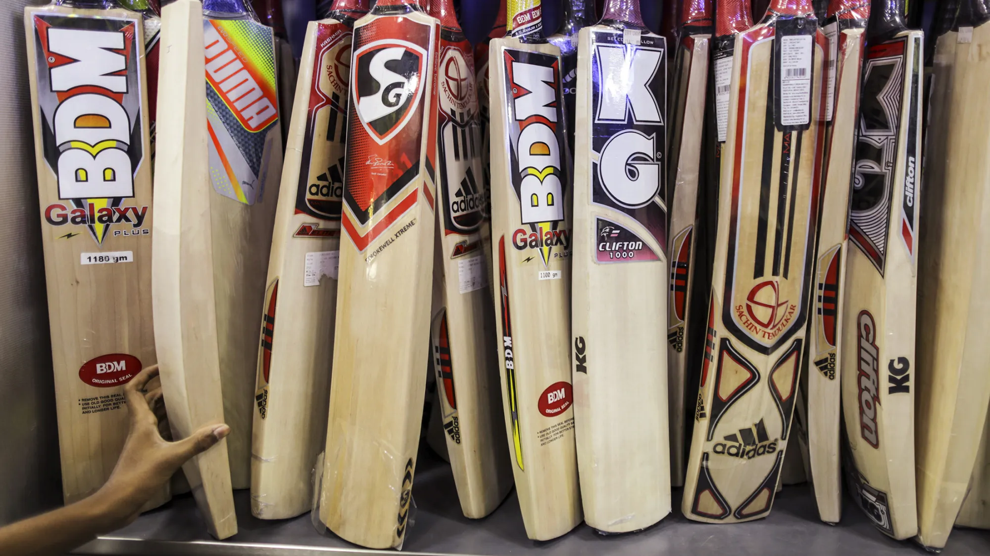A shopper picks out a cricket bat on display at sports store in Mumbai, India, on Sunday, March 6, 2016. India is set to play its opening game against New Zealand at the Vidarbha Cricket Association Stadium in Nagpur as part of the sixth ICC World Twenty20 cricket tournament on March 15.
