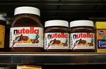 Jars of Nutella are displayed on a shelf at a market.
