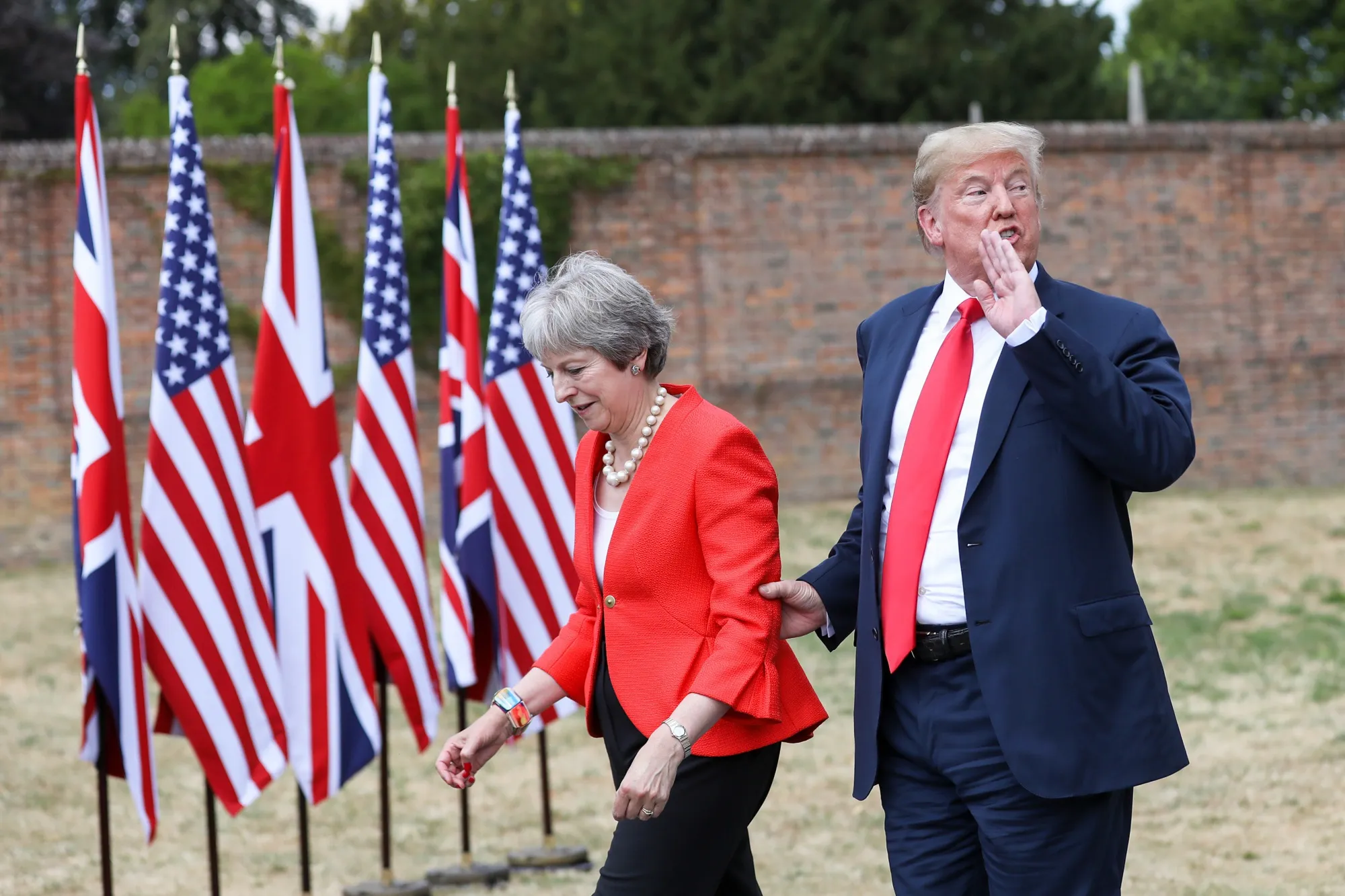 Trump speaks to the media as he holds onto Theresa May.