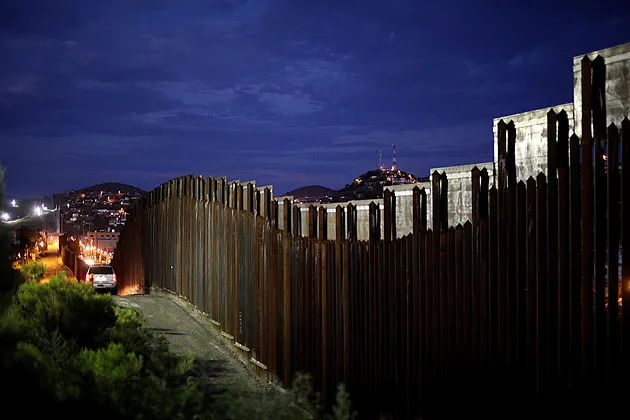 The U.S.-Mexico border wall is illuminated at night in Nogales, Ariz.