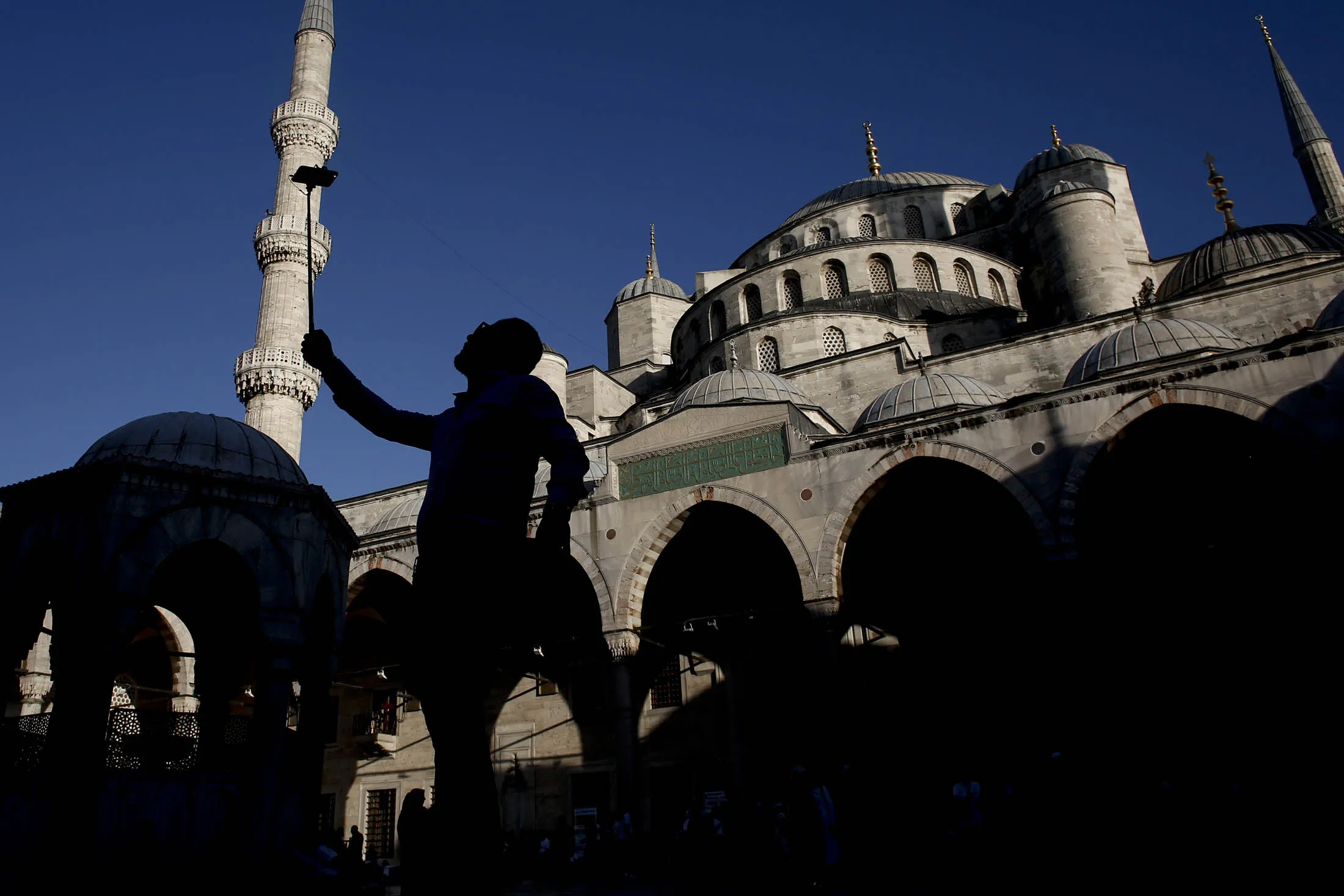 A tourist uses a selfie stick to photograph himself at the Sultanahmet mosque, also known as Hagia Sophia, in Istanbul, Turkey, on Sunday, Oct. 2, 2016. Turkish food prices showed the biggest monthly drop seen in September, bringing annual consumer inflation to the lowest level in over a year and giving more leeway to monetary policy makers to cut borrowing costs this month.
