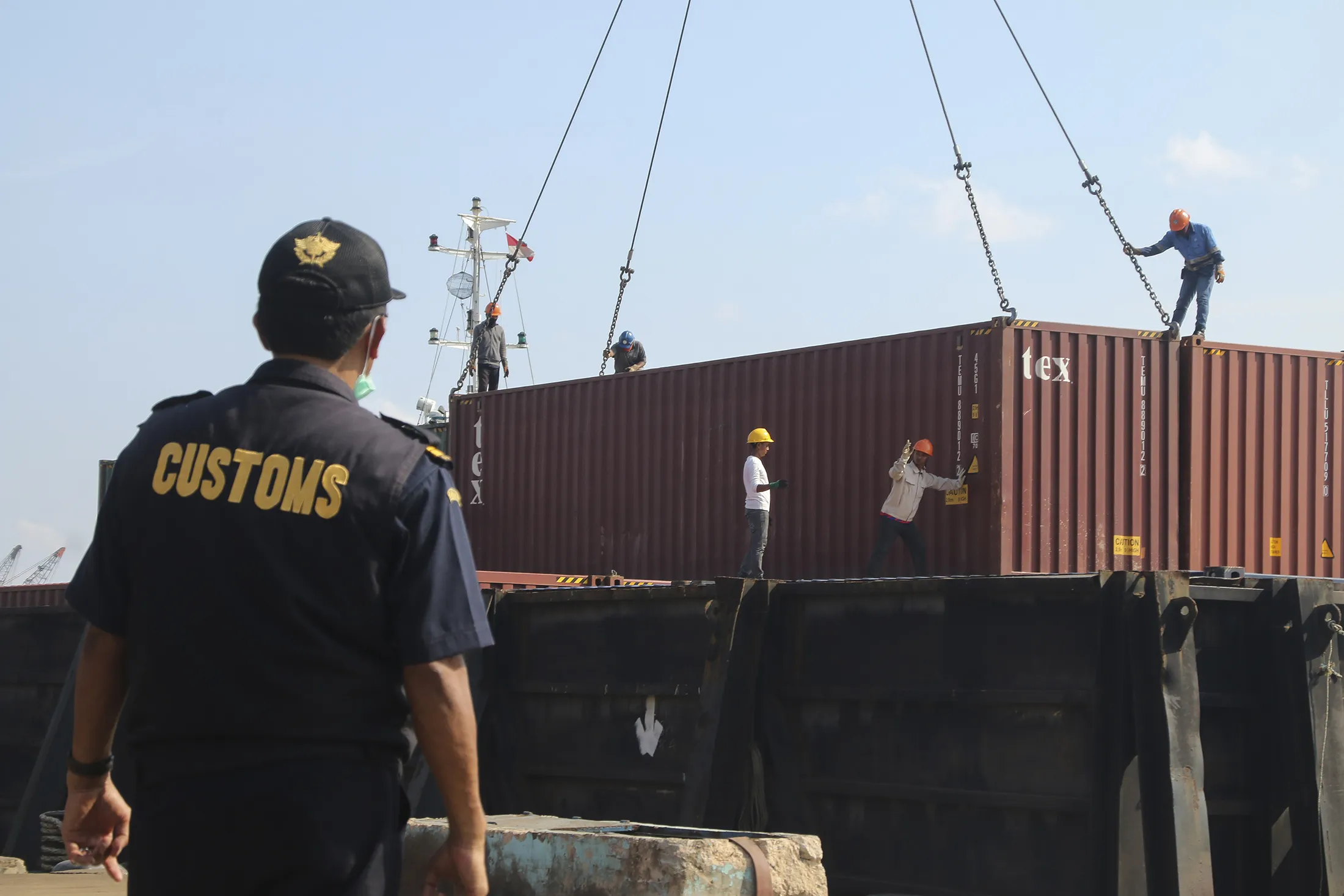 An Indonesian custom officer stands as workers handle a container in Batam port on July 29.