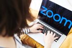 The logo for the Zoom Video Communications Inc. application is displayed on an Apple Inc. laptop computer in an arranged photograph.