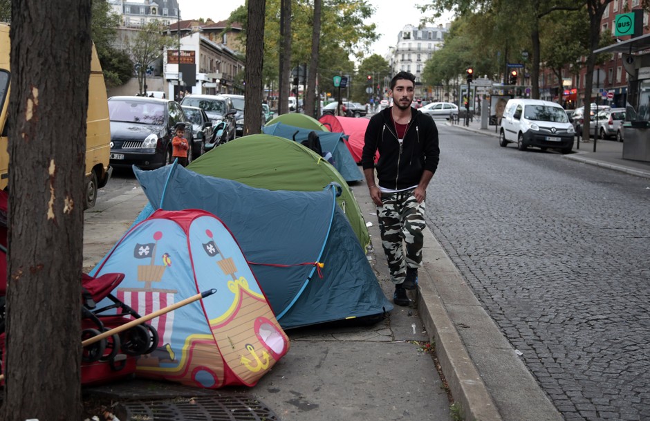 Ehab Ali Naser, a 23-year-old Syrian refugee, walks past tents at a makeshift camp in Paris.