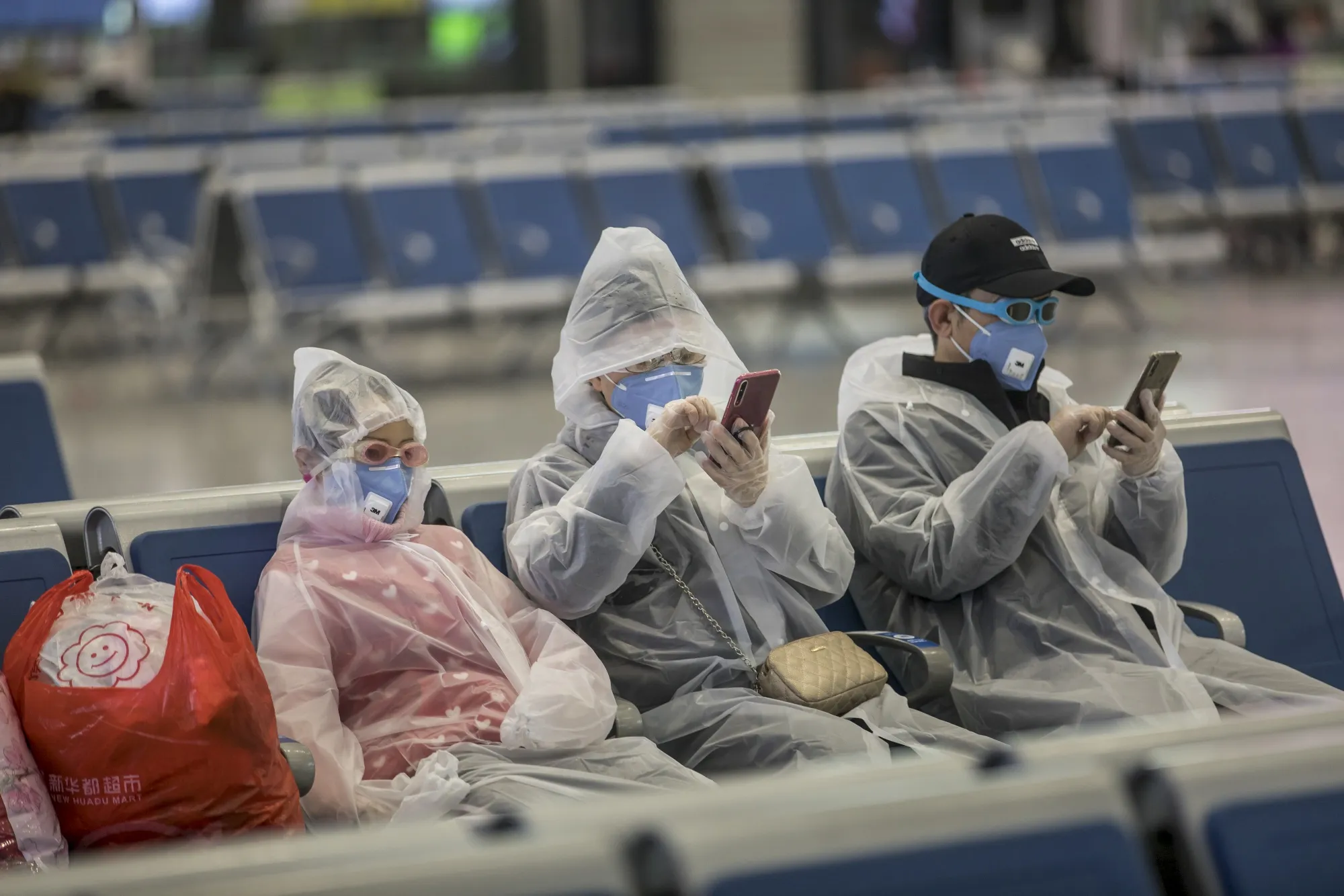 A family wearing masks and make-shift protection gear wait for their train at the Hongqiao Railway Station in Shanghai.