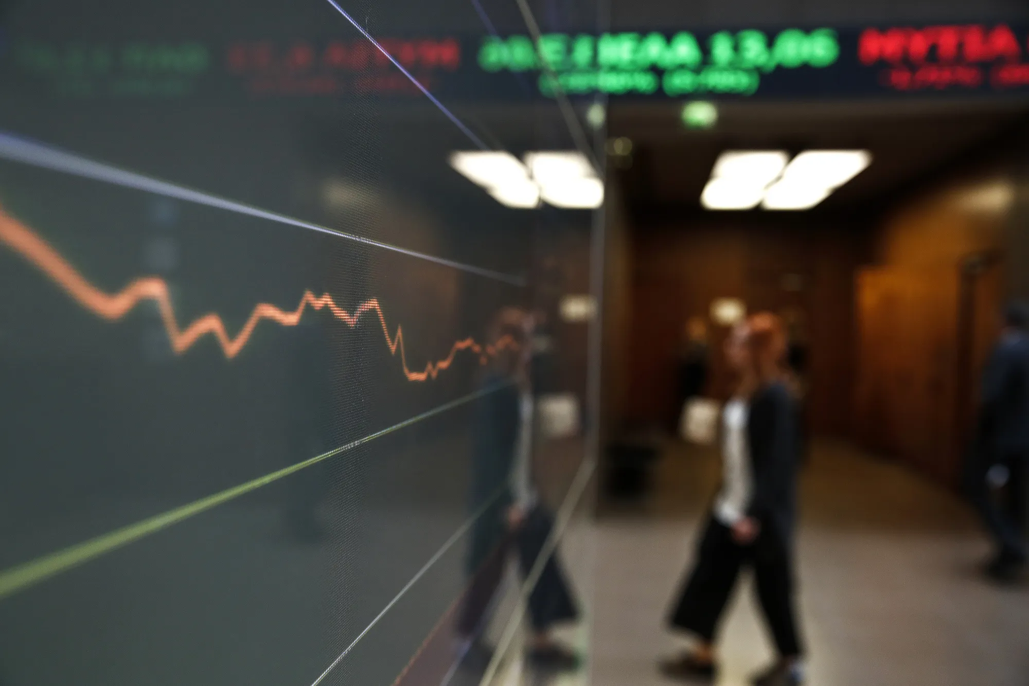 An employee passes an electronic index curve displaying current share prices in the Hellenic Exchanges - Athens Stock Exchange SA in Athens, Greece, on Wednesday, Feb. 1, 2017. Greek assets have been roiled since Thursday after a meeting between Finance Minister Euclid Tsakalotos and the nations bailout auditors ended in disagreement last week.