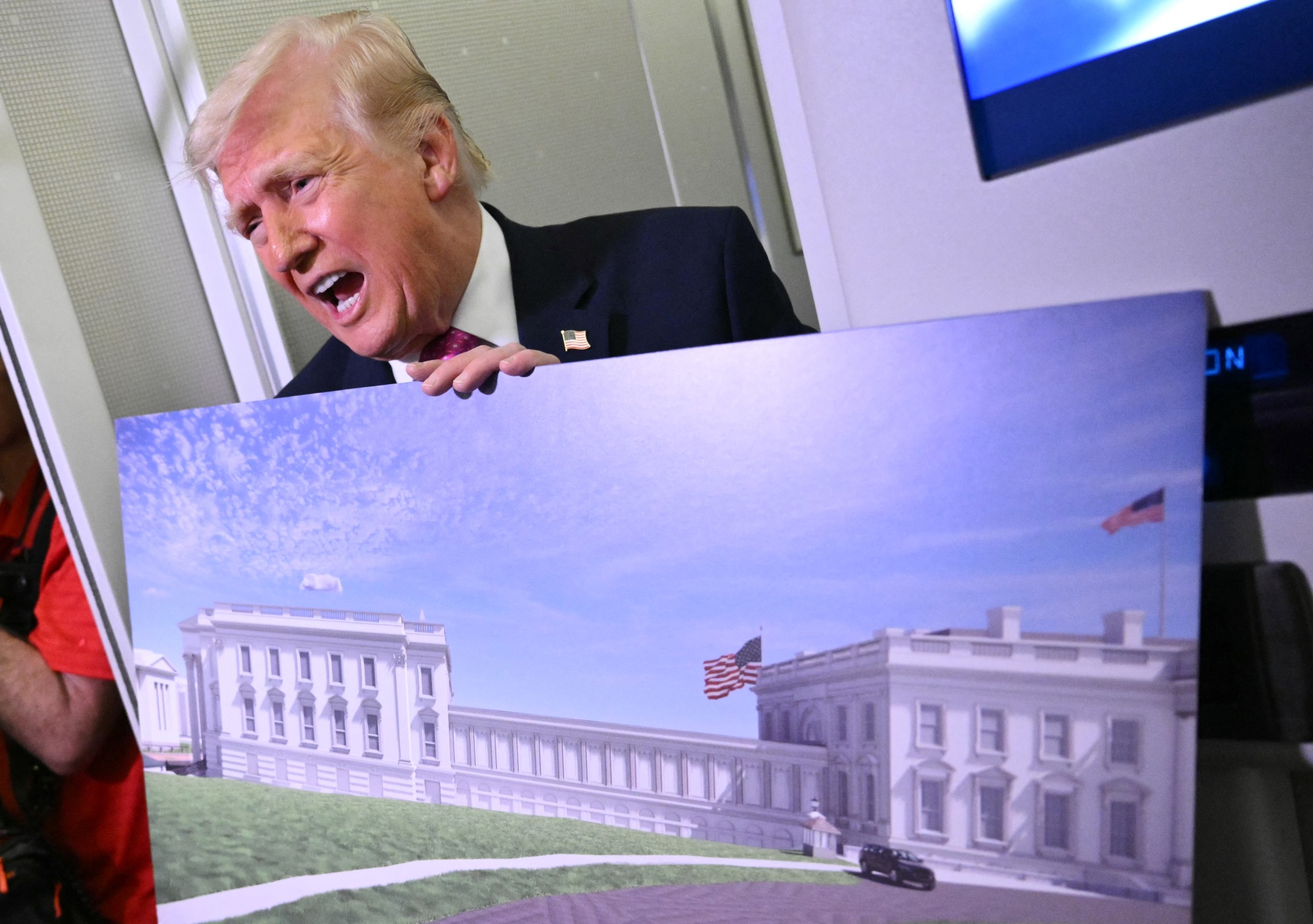 US President Donald Trump holds a rendering of the East Wing modernization as he speaks to reporters aboard Air Force One en route to Joint Base Andrews, Maryland, on March 29, 2026. President Donald Trump said March 29 the US military was planning a large complex beneath the new ballroom he is building at the White House. "The military is building a massive complex under the ballroom, and that's under construction, and we're doing very well, so we're ahead of schedule," Trump told reporters aboard Air Force One, returning to White House after spending the weekend at his Mar-A-Lago residence. (Photo by Mandel NGAN / AFP via Getty Images) Photographer: MANDEL NGAN/AFP