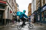 A takeaway food courier, working for Deliveroo, cycles past food outlets in London.