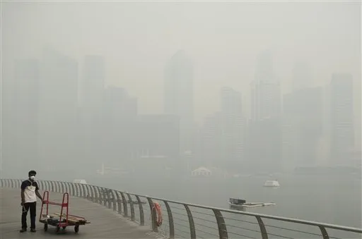 A worker wears a mask to protect from a haze blanketing the Singapore Central Business District, skyline in the background on Thursday, June 20, 2013.
