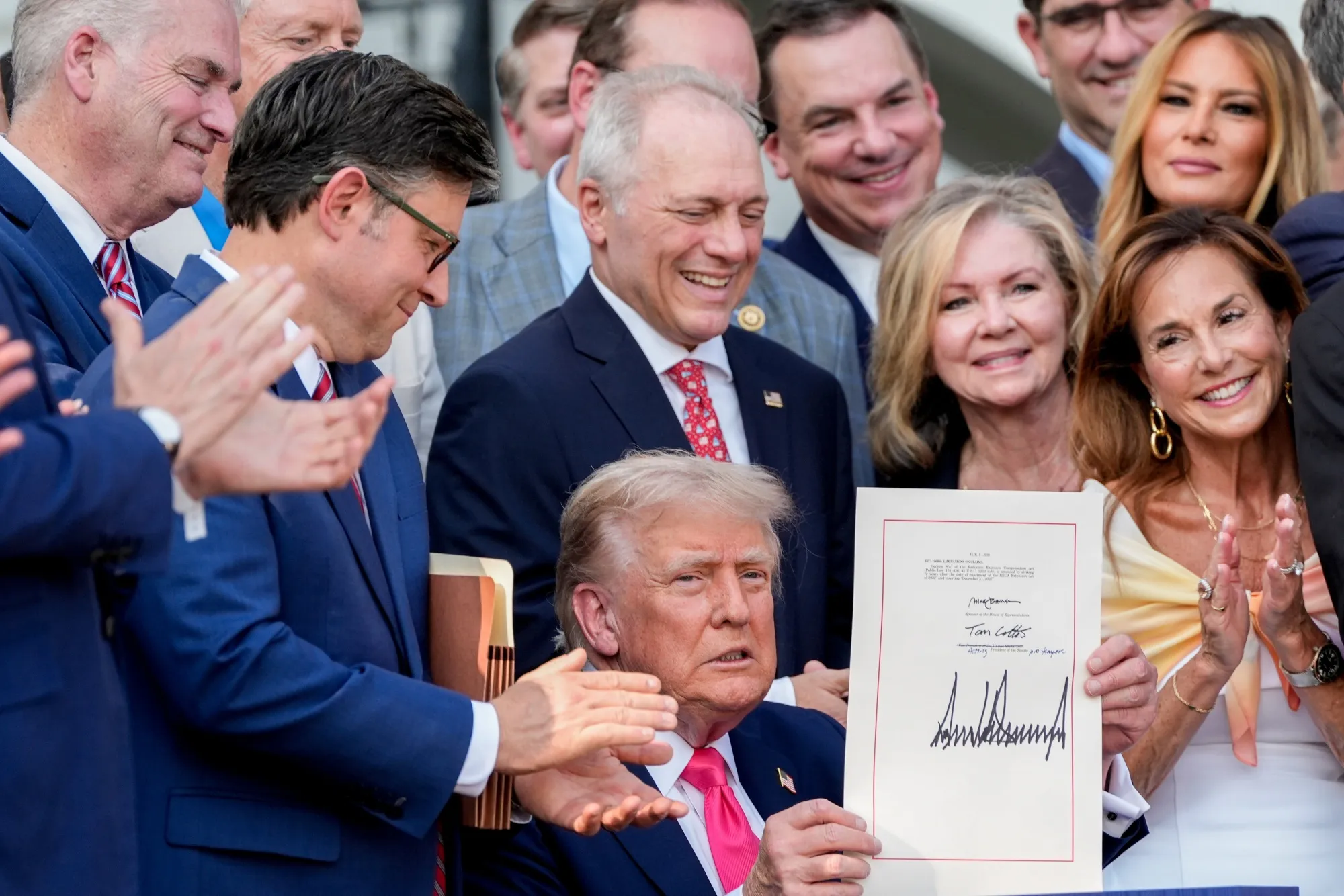 Donald Trump, surrounded by congressional Republicans, displays the signed tax bill during on July 4.
