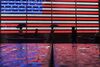 People walk past an illuminated American flag in Times Square during a rain storm on September 25, 2018 in New York City.