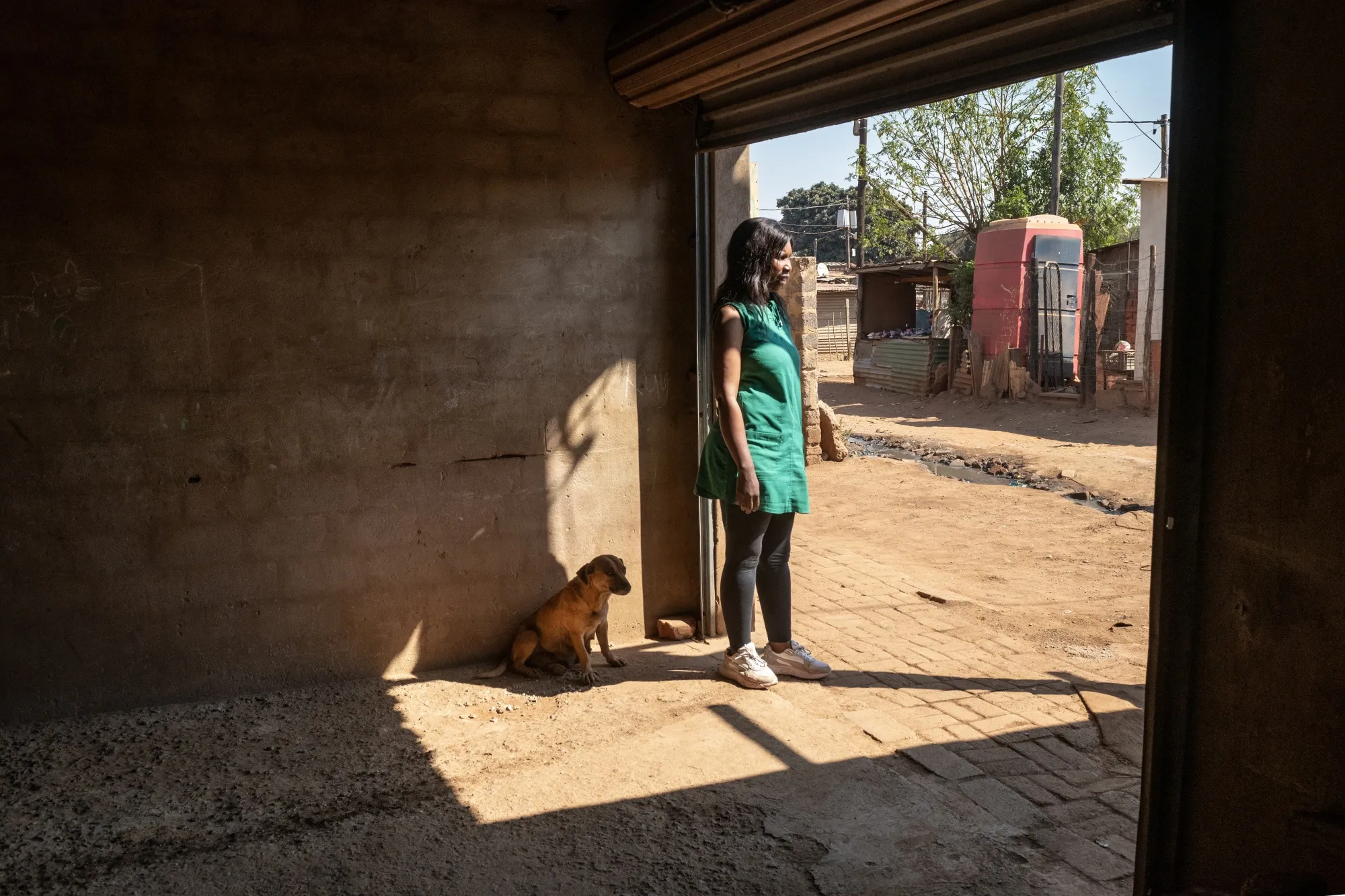 Community member Noluthando Geja stands in a makeshift car port near her home.