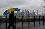 A man with an umbrella walks past the New York City Skyline on January 19. 