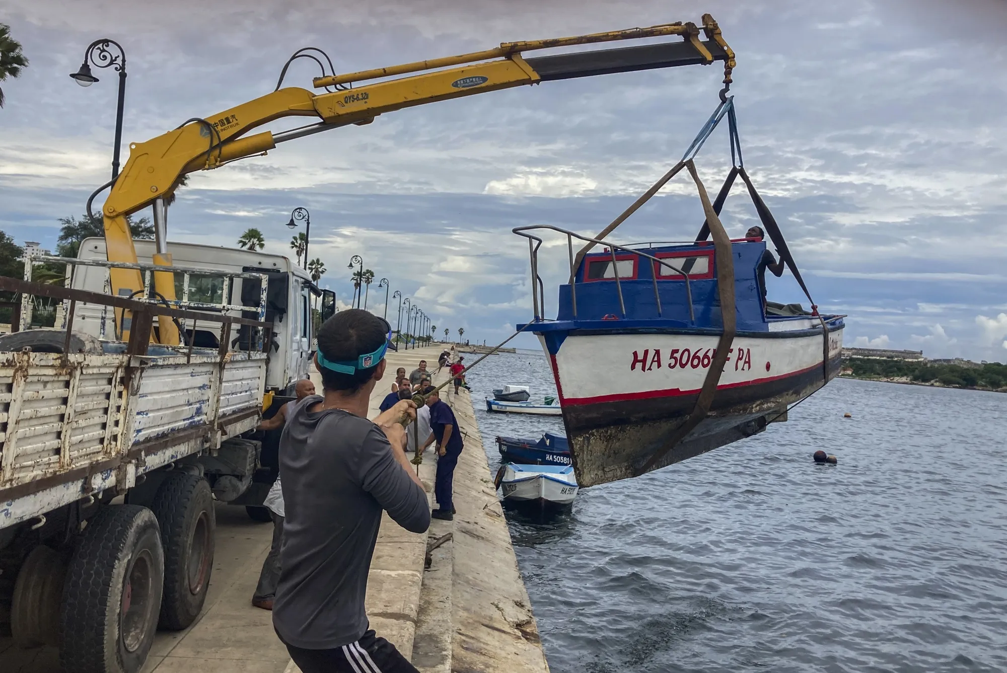 Workers remove a boat from the water in the bay of Havana, Cuba, Monday, Sept. 26, 2022. Hurricane Ian was growing stronger as it approached the western tip of Cuba on a track to hit the west coast of Florida as a major hurricane as early as Wednesday. (AP Photo/Milexsy Duran)