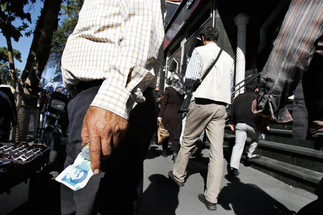 A money changer holds an Iranian banknote on Ferdowsi Street in Tehran